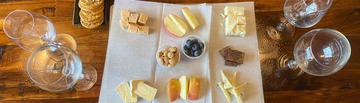 Wine and Cheese pairing from above. A board with a variety of cheeses surrounded by wine glasses
